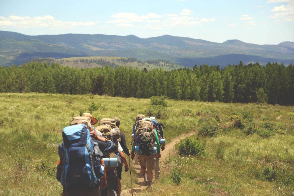 Abbildung zeigt Wander Gruppe mit Rucksack Wander Tour in den Bergen auf Hüttentour mit Hüttenschlafsack und Isomatte Sportsocken Wandersocken von Wanderer Wandern in Bergen